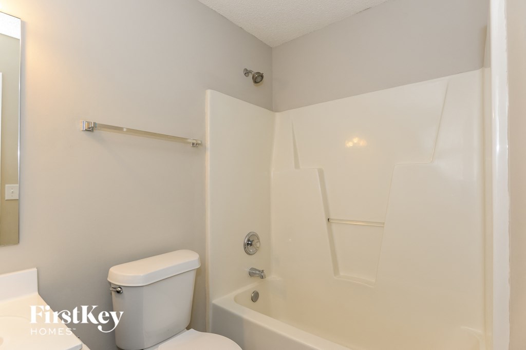 A white toilet sits next to a white bathtub in a bathroom.