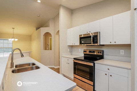 a kitchen with white cabinets and black appliances and a sink