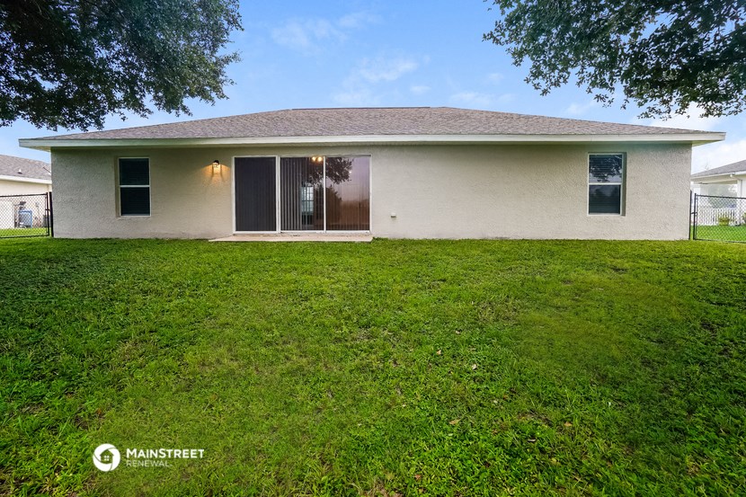 the backyard of a house with a lawn and a patio