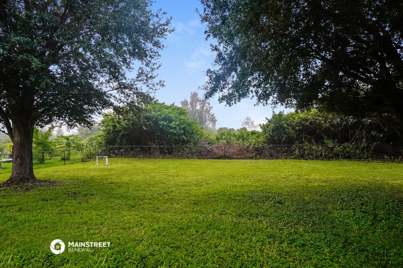 a soccer field in a park with trees and a fence