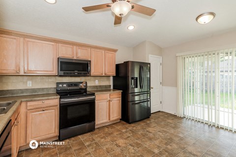 a kitchen with wood cabinets and black appliances and a window