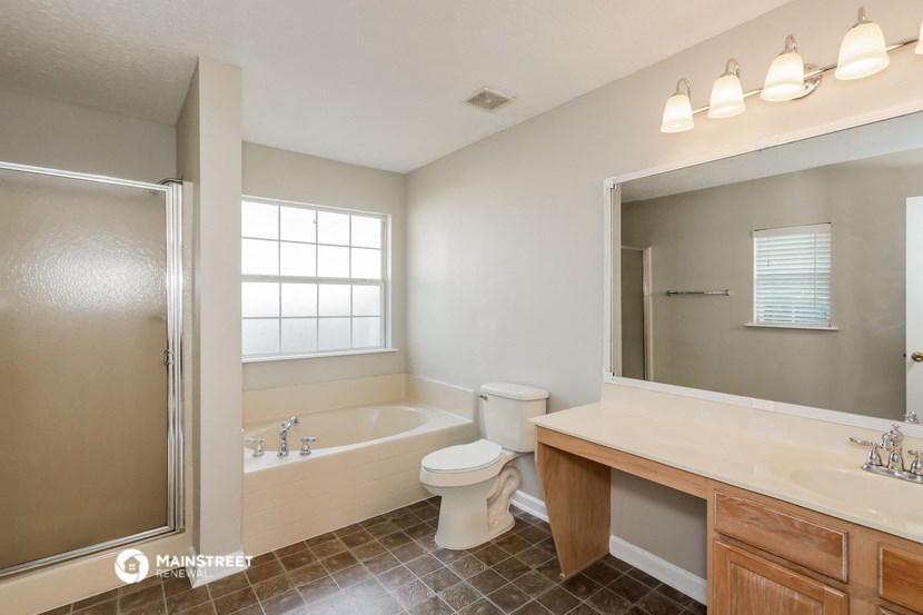 a bathroom with a large mirror and a tub and a toilet