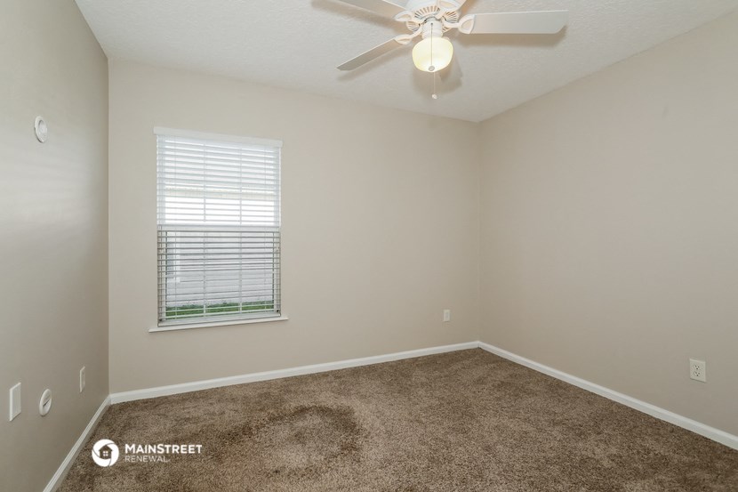 an empty bedroom with a ceiling fan and a window