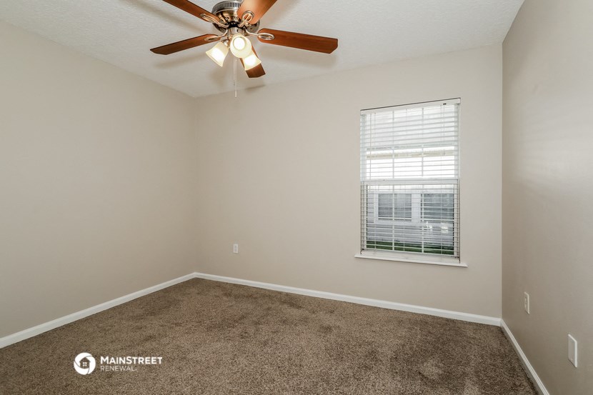 the spacious bedroom with carpet and a ceiling fan