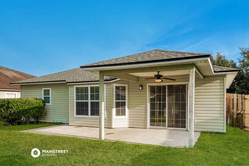 a small tan house with a porch and a ceiling fan
