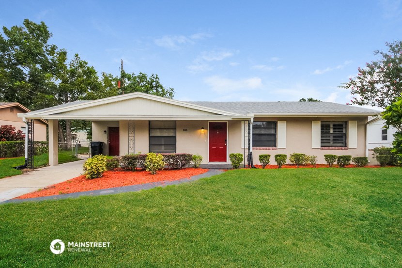 a white house with a red door and a lawn