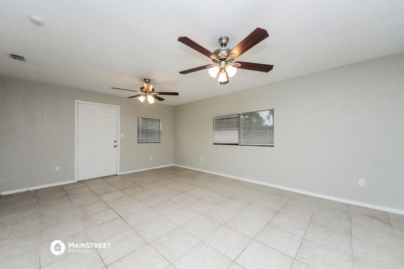 the spacious living room with ceiling fan and tile flooring