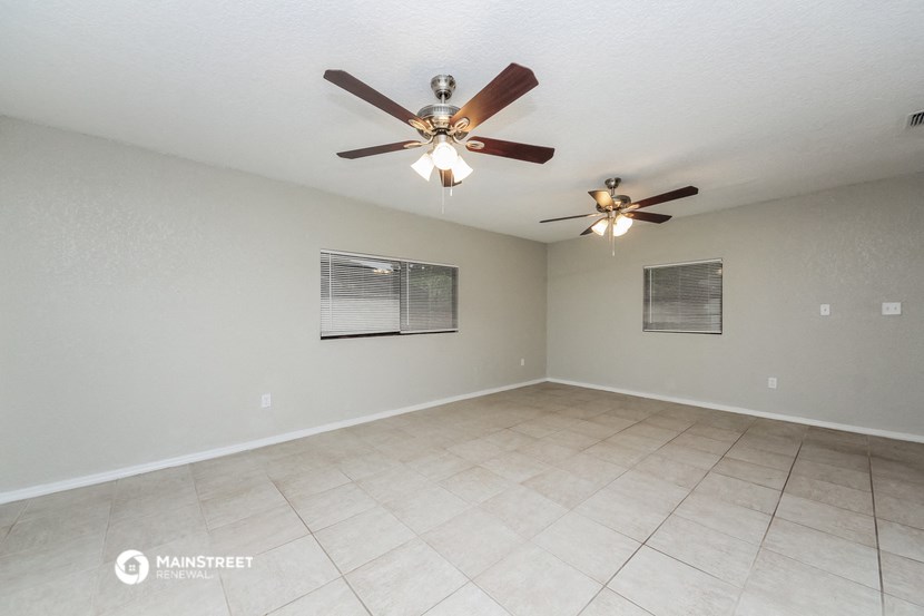 the spacious living room with ceiling fan and tile flooring