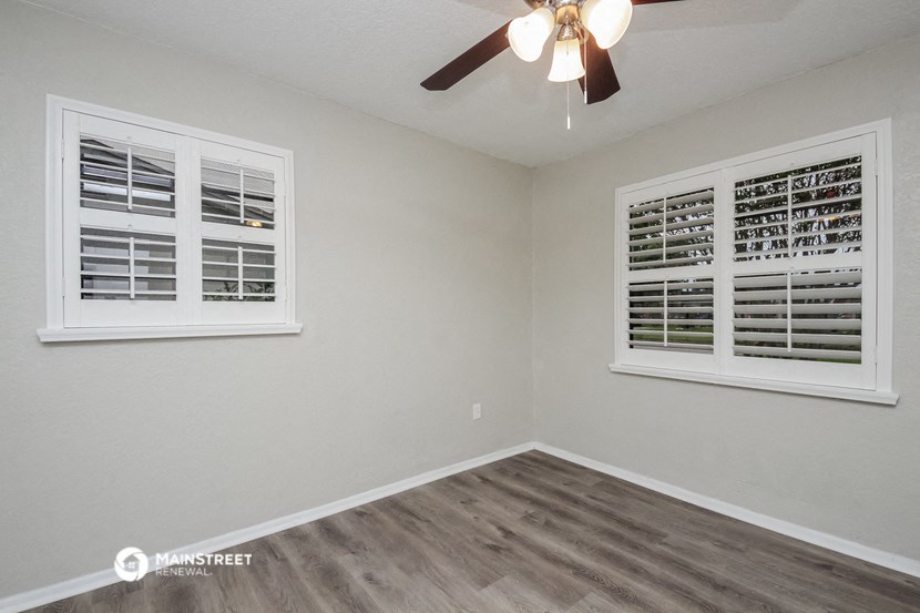 the living room of a home with a ceiling fan and two windows