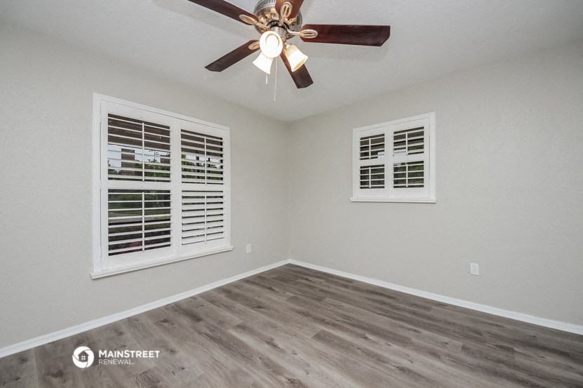 the bedroom has a ceiling fan and two windows