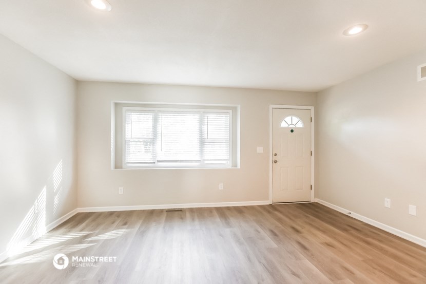 the spacious living room with hardwood floors and a white door