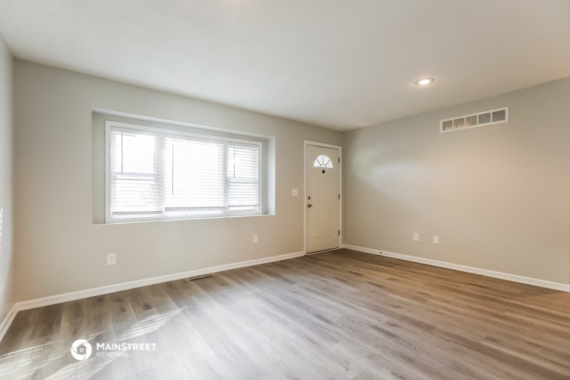 the spacious living room with hardwood flooring and a window