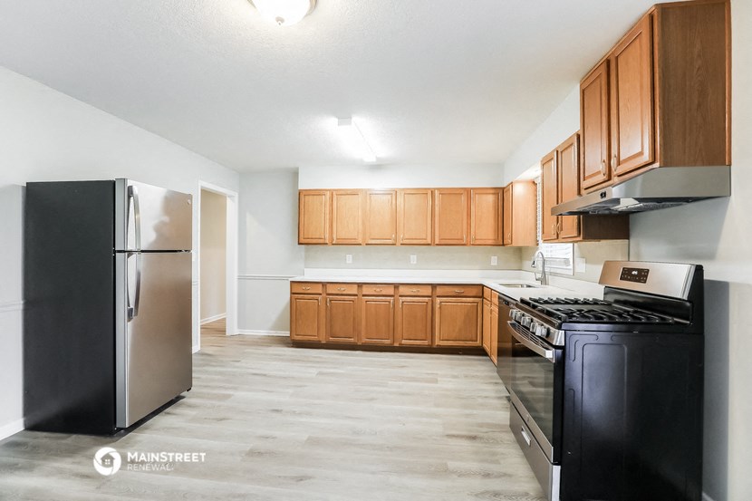an empty kitchen with black appliances and wooden cabinets
