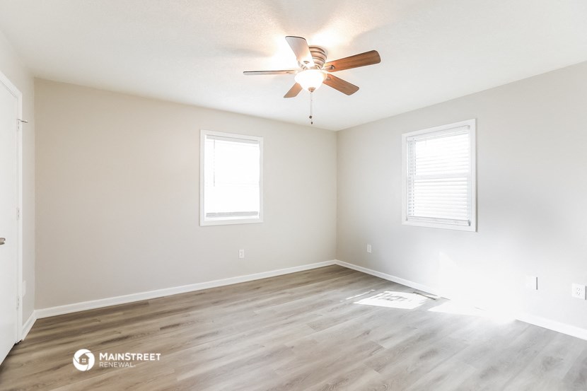 the spacious living room with hardwood floors and a ceiling fan
