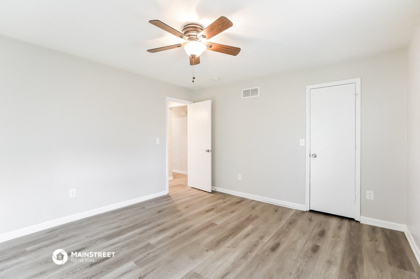 the spacious living room with wood flooring and a ceiling fan