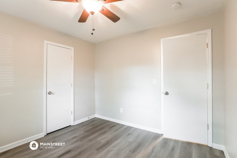 a bedroom with white walls and a ceiling fan