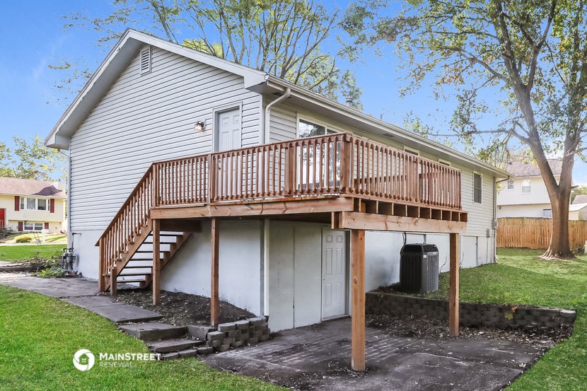 a white house with a wooden deck on top of a garage