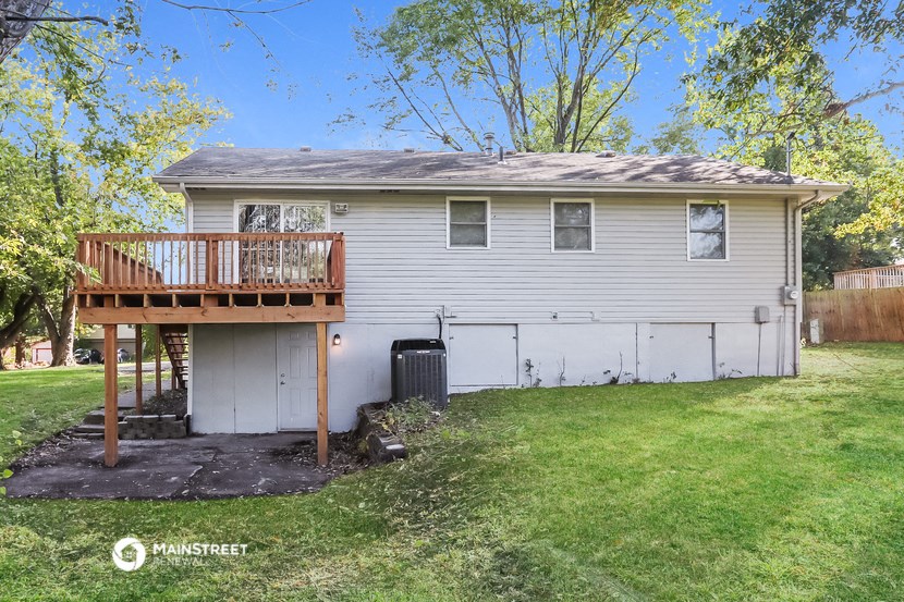 a backyard with a garage and a white house with a deck