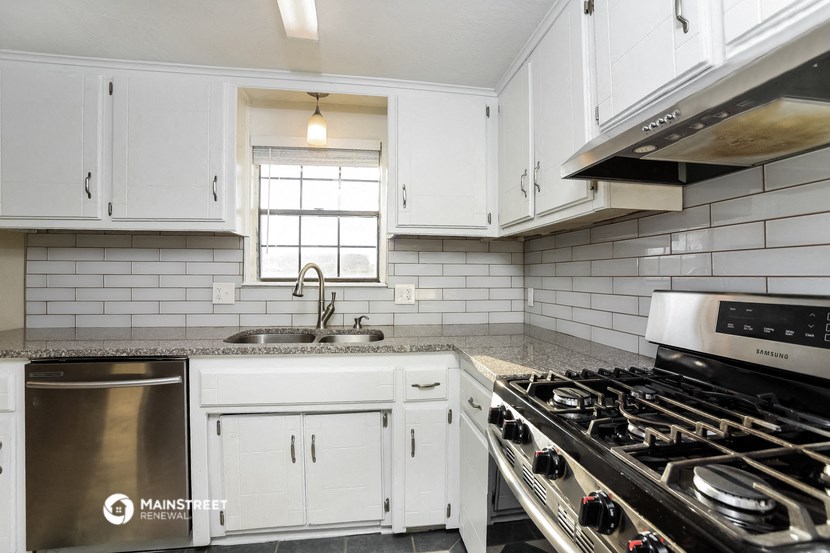 a white kitchen with stainless steel appliances and white cabinets