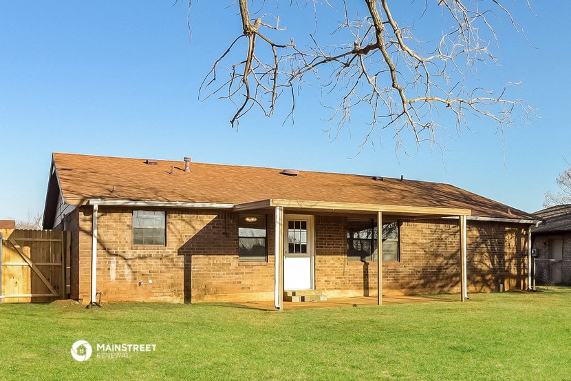 a brick house with a porch and a tree