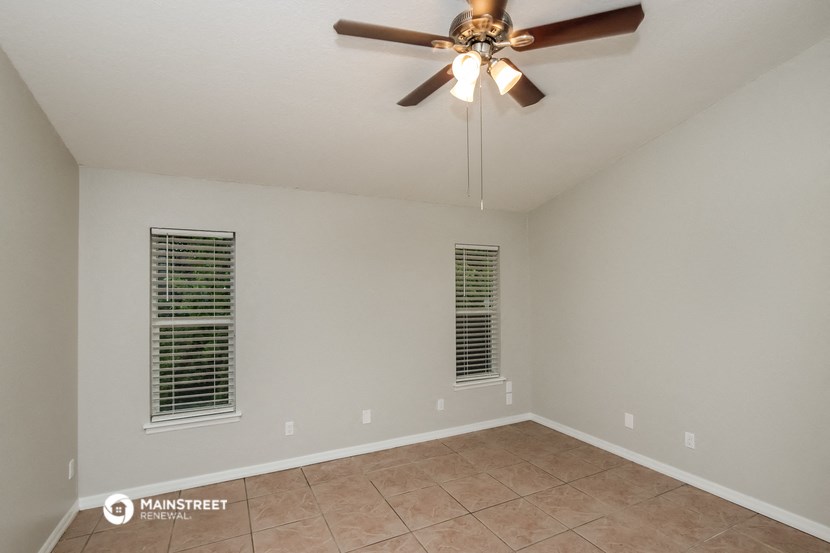 the spacious living room with ceiling fan and tile flooring