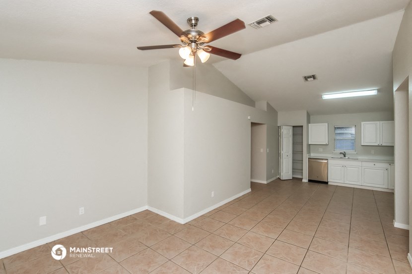 an empty living room with a ceiling fan and a tiled floor