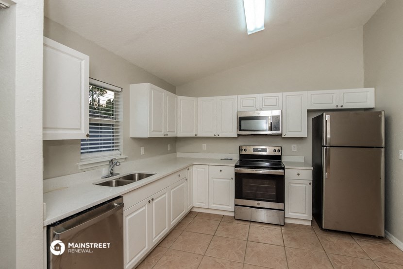 the kitchen has stainless steel appliances and white cabinets