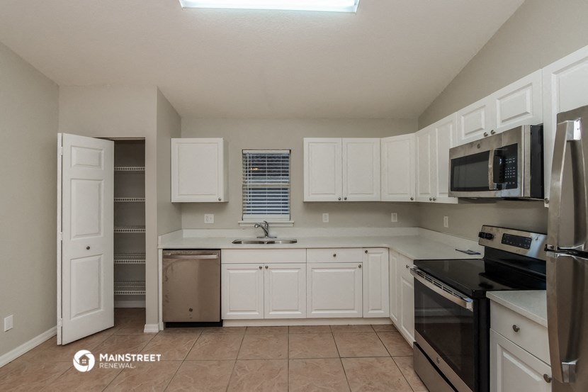 a kitchen with white cabinets and black appliances