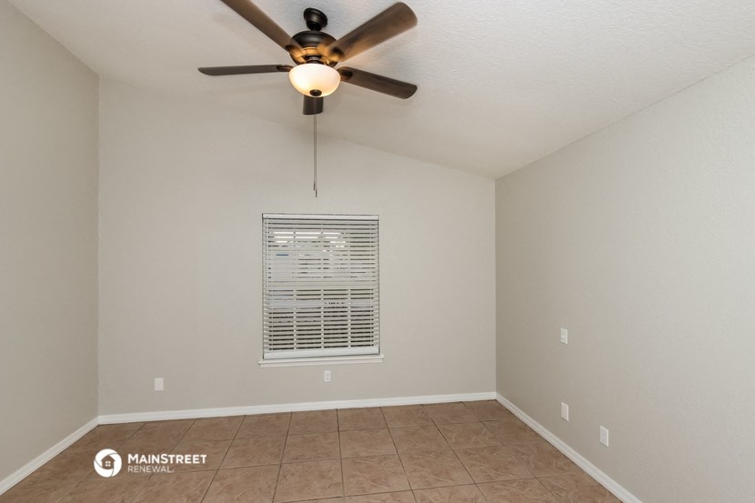 the spacious living room has a ceiling fan and tile flooring