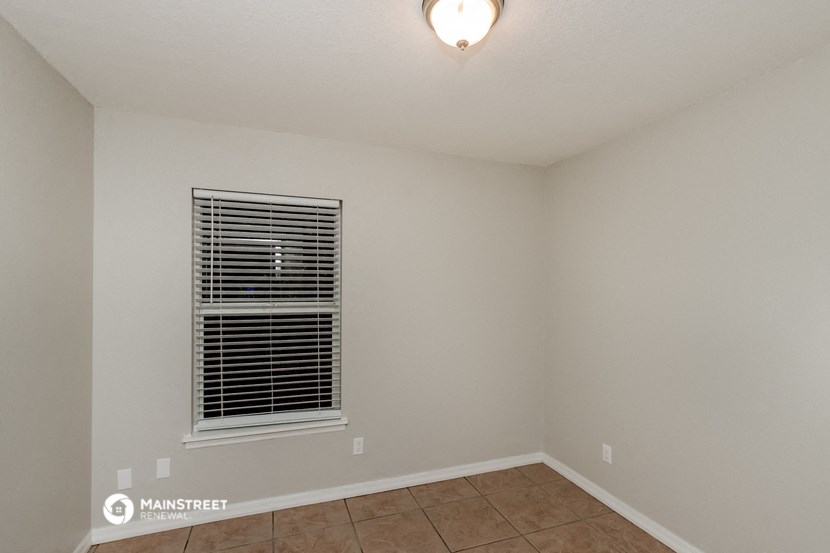the living room of an empty home with a window and a lamp