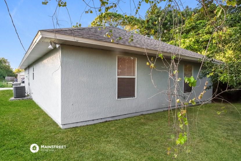 the backyard of a house with a lawn and a tree