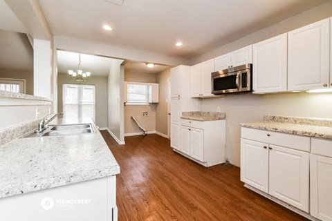 an open kitchen with white cabinets and marble counter tops
