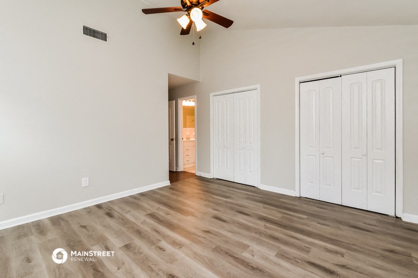 an empty living room with white walls and a ceiling fan