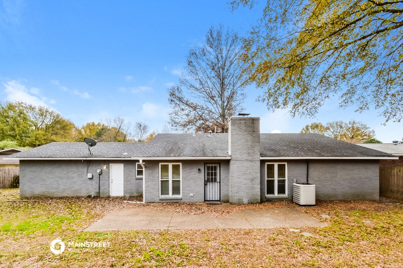 a small gray house with a yard and a tree