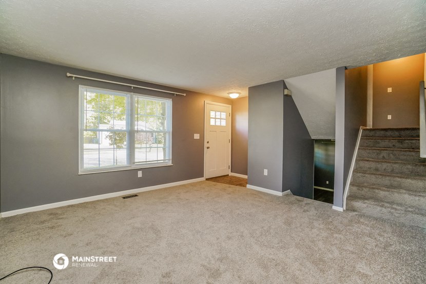 an empty living room with a staircase and a window