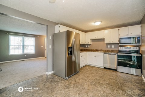 a kitchen with white cabinets and a stainless steel refrigerator