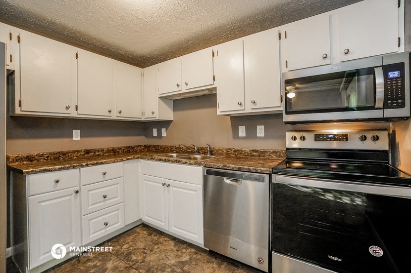a kitchen with white cabinets and black appliances and granite counter tops