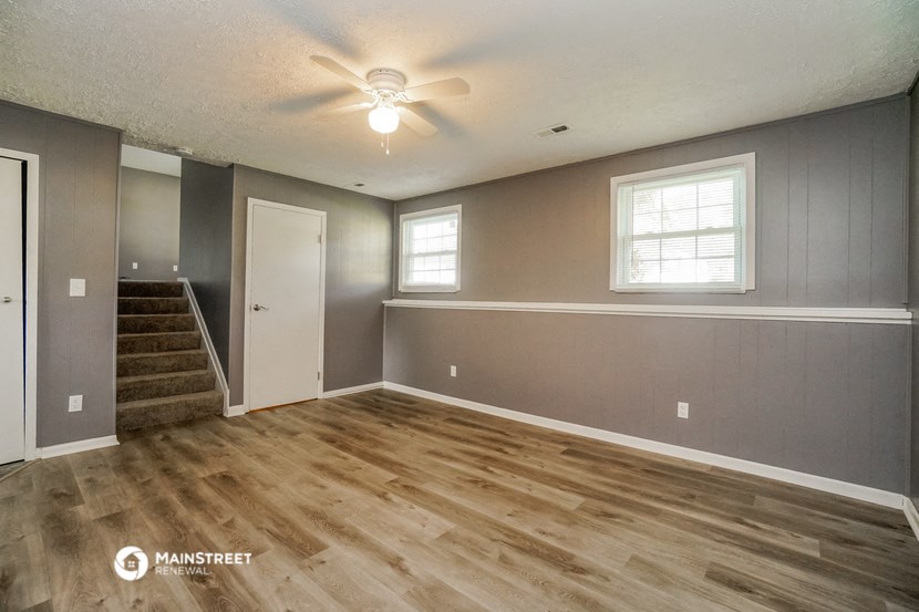 an empty living room with wood floors and a ceiling fan