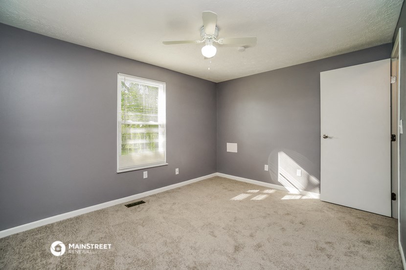 an empty room with a ceiling fan and a window