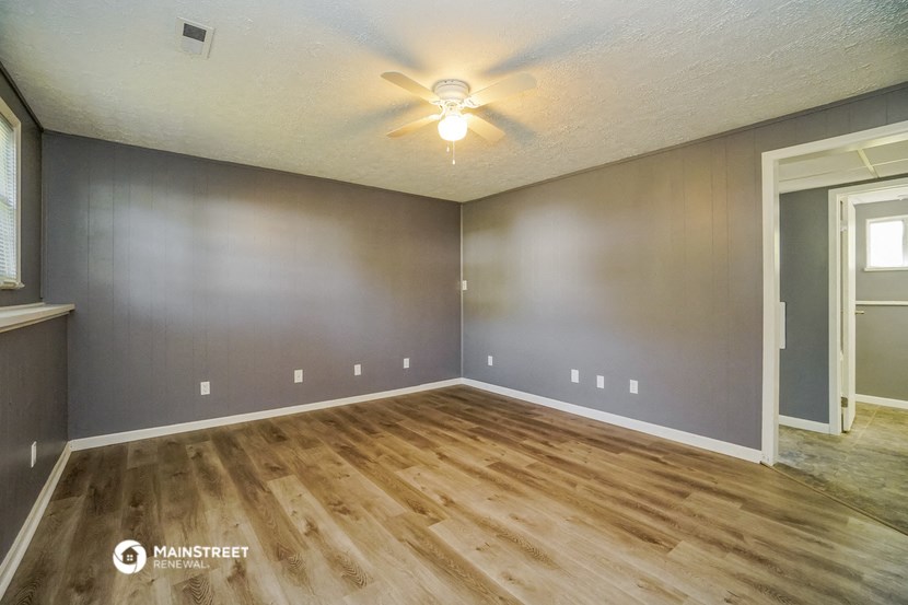 the living room of an empty house with a ceiling fan