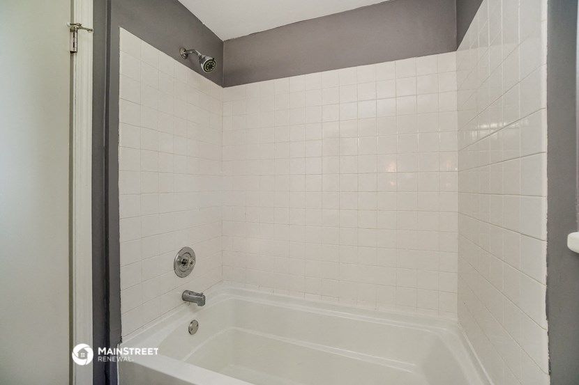 a white tiled bathroom with a tub and a shower