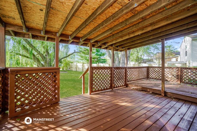 a covered porch with a view of a yard and a house