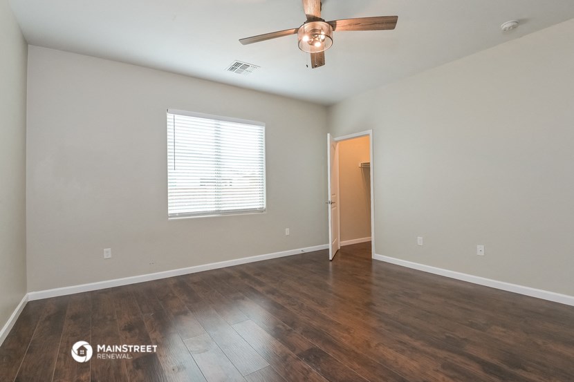 the spacious living room with hardwood floors and a ceiling fan