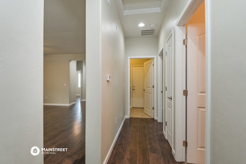 a hallway with wood flooring and white walls and a door to a bedroom