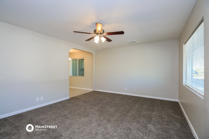 an empty living room with a ceiling fan and a window