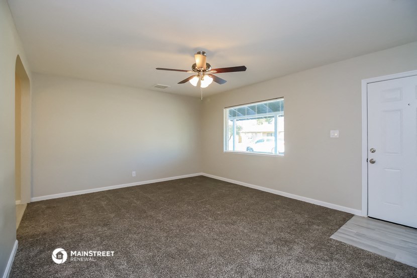 the spacious living room with carpet and ceiling fan