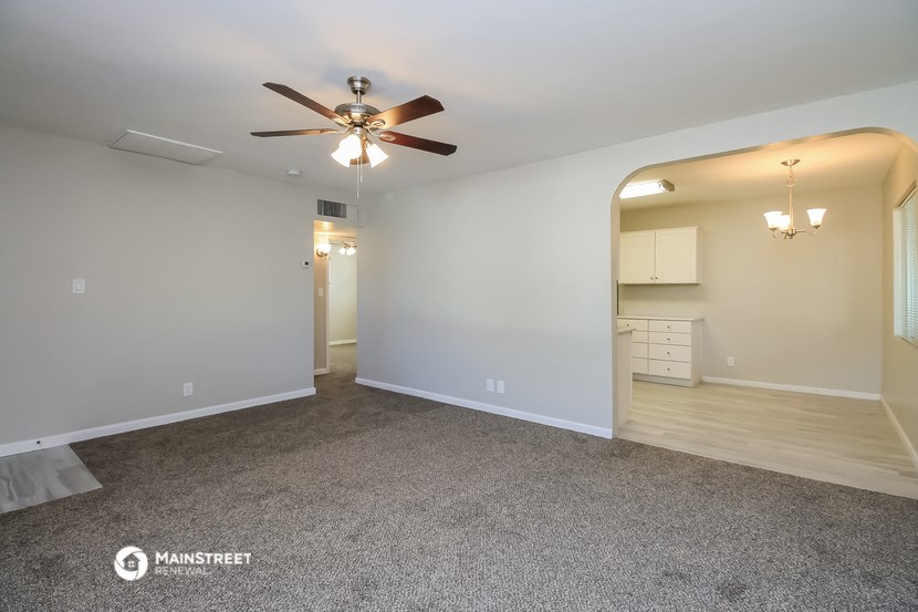 the living room and dining room with ceiling fan and carpet