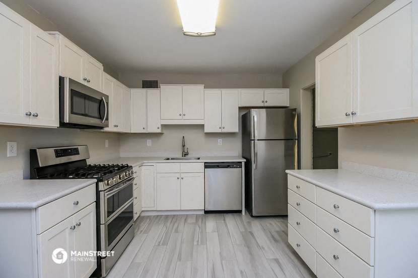 a white kitchen with stainless steel appliances and white cabinets