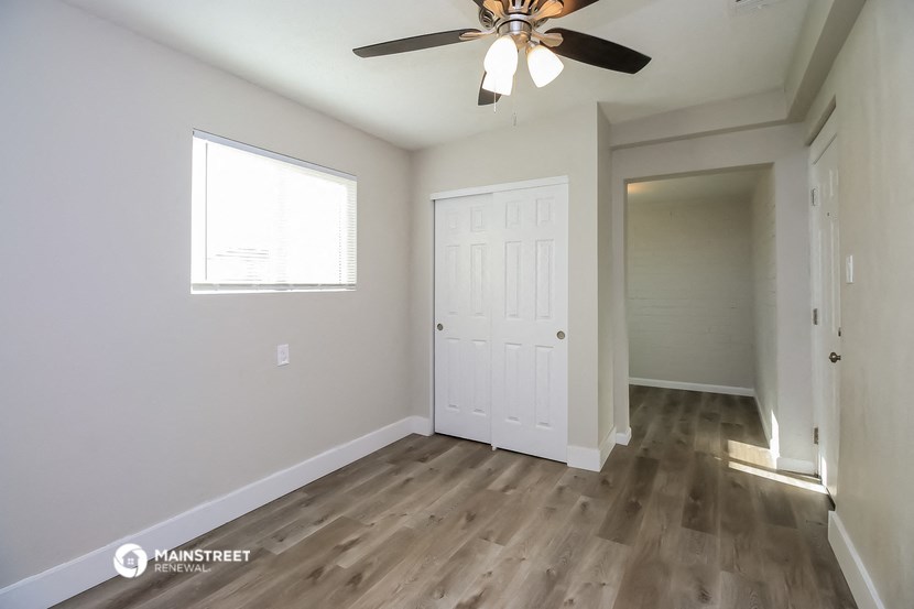 an empty living room with a ceiling fan and a door