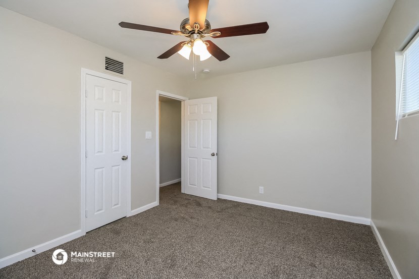the spacious living room with ceiling fan and closet